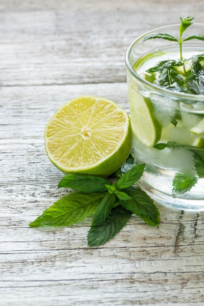 Mojito cocktail au citron vert et menthe dans un verre à whisky sur un fond en bois blanc