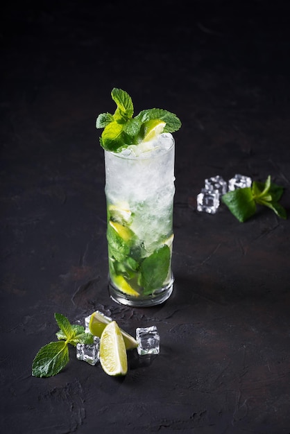 Mojito cocktail avec glaçons citron vert et menthe dans un verre highball sur fond noir avec espace de copie Mise au point sélective