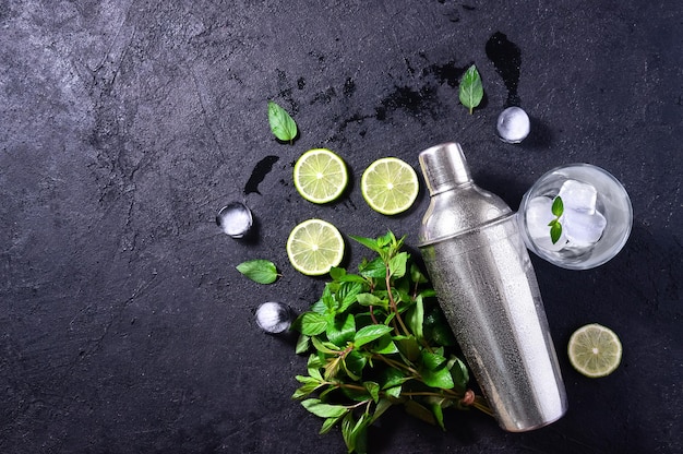 Mojito Cocktail Making Mint Lime Ice Glass et Bar Shaker sur table en pierre sombre Copiez l'espace pour votre texte