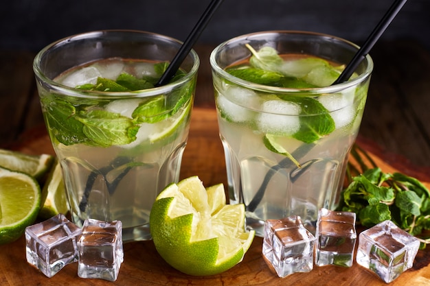 Mojito frais dans des verres avec des glaçons sur la table en bois.