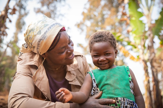 Photo moment d'amour et de tendresse entre mère et fille africaines souriant tout-petit fille africaine avec sa mère concept de la fête des mères