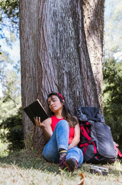 Moment de camping paisible Femme lisant un livre avec les bras levés sous l'arbre