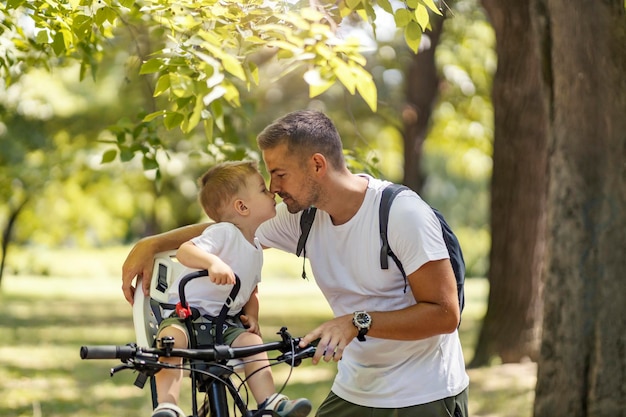 Moment émotionnel en famille Père et fils font du vélo à travers les bois par une journée d'été ensoleillée