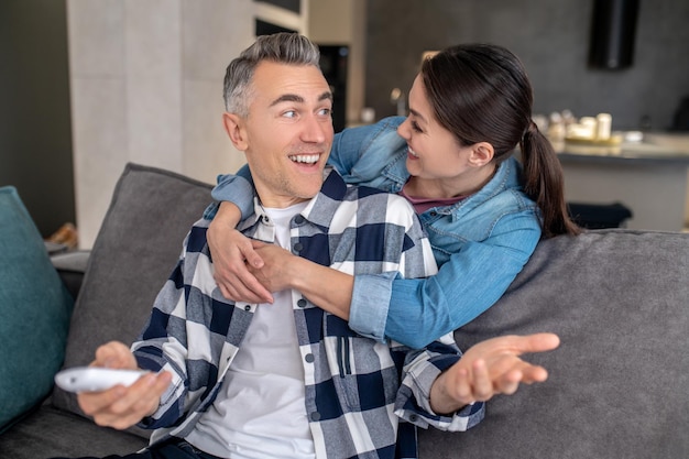 Moment heureux Femme heureuse regardant un homme extatique assis sur un canapé à la maison