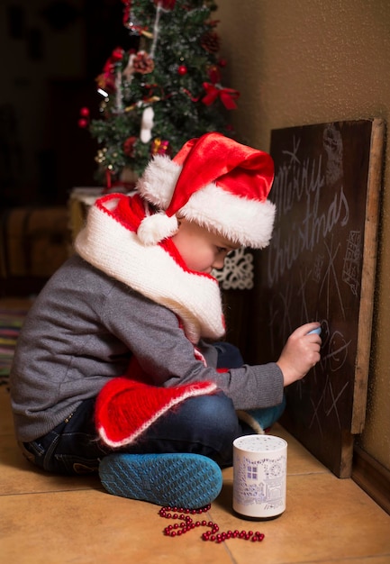 Photo moments d'enfance concept de vacances de noël garçon à côté de l'arbre de noël à la maison joie et bonheur