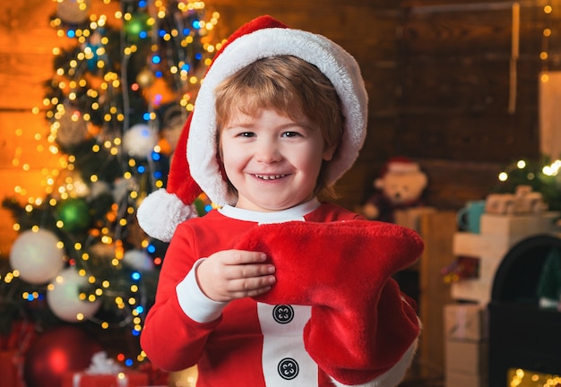 Moments d'enfance. Le visage joyeux de l'enfant a reçu un cadeau en chaussette de Noël.