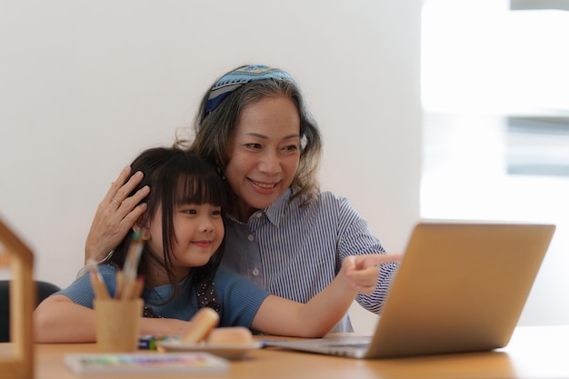 Moments heureux de grand-mère asiatique avec sa petite-fille utilisant un appel vidéo Activités de loisirs pour les enfants à la maison