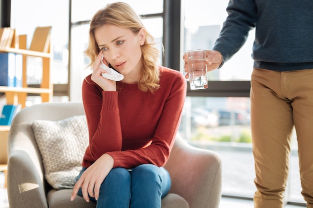 Des Moments Stressants. Agréable Malheureuse Jeune Femme Assise Dans Le Fauteuil Et Pleurer En Pensant à Ses Problèmes Personnels