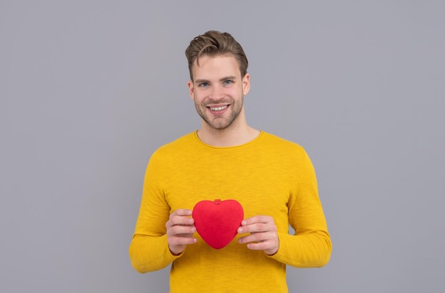 Mon cœur pour vous. Sourire de beau mec tenant un coeur rouge. Joyeuse saint Valentin. 14 février. Faites plaisir à votre amour avec un cadeau.