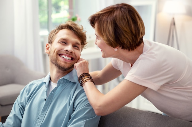 Mon garçon. Belle femme agréable touchant la joue de son fils tout en montrant son affection