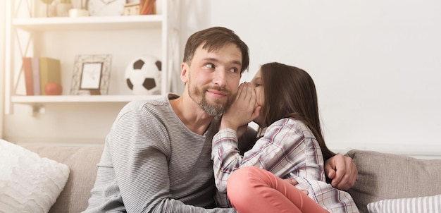 Mon secret. Petite fille chuchotant dans l'oreille du père, concept de confiance familiale