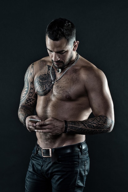 Mon téléphone portable est mon meilleur ami. Homme avec tatouage sur corps musclé. Un homme musclé utilise un téléphone portable. Tatouage et art corporel. Le sport consiste avant tout à jouer et à concourir.