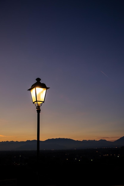 Moncalieri Italie magnifique lampadaire au coucher du soleil dans le ciel de montagnes et de maisons de fond