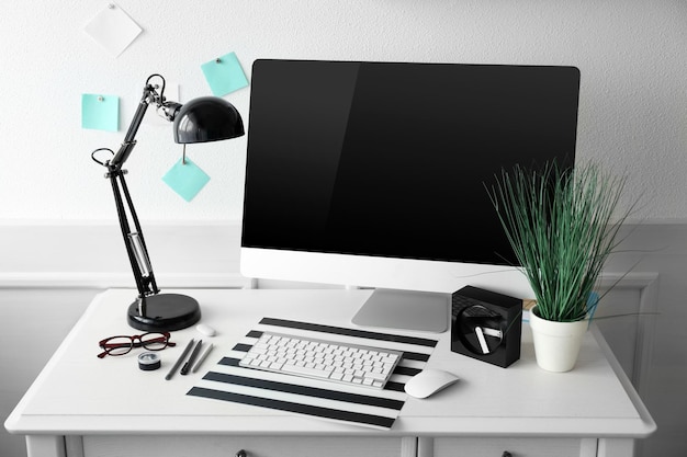 Moniteur à écran large moderne avec lampe sur table blanche à l'intérieur de la pièce