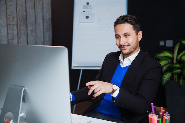 Moniteur d'ordinateur de travailleur de bureau enthousiaste bel homme d'affaires