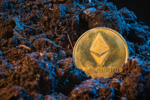 Monnaie crypto minière - Ethereum, pièce de monnaie en ligne dans le sol de terre.