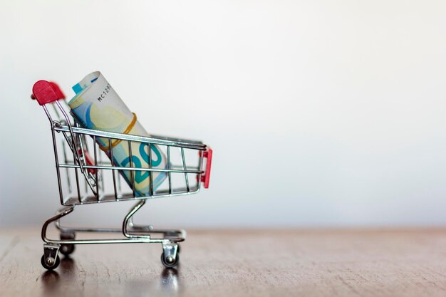 Monnaie et panier d'achat sur la table sur un fond blanc