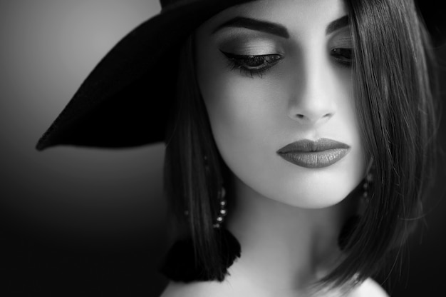 Monochrome Gros Plan D'un Magnifique Jeune Mannequin Féminin élégant Posant Sensuellement Portant Du Maquillage Professionnel Et Un Chapeau Beauté Cosmétiques Lèvres Peau Yeux Coiffure Tenue Rétro Vintage Concept.