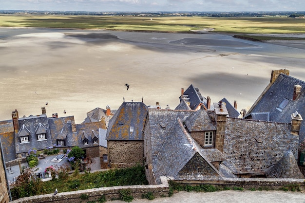 Mont Saint Michel, France. Vue sur les maisons, les toits, les murs du village et l'océan à marée basse.