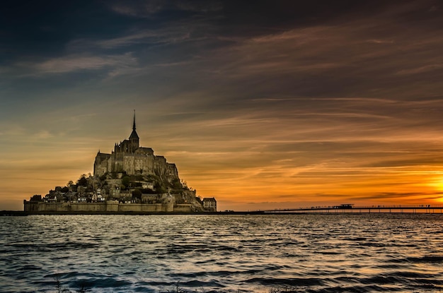 Photo le mont-saint-michel par la mer contre le ciel au coucher du soleil