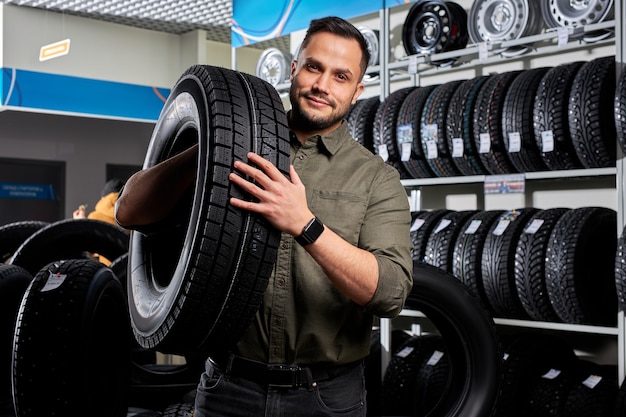 Montage de pneus client dans le service automobile, mécanicien automobile vérifie la sécurité du pneu et de la bande de roulement en caoutchouc, concept: réparation de machines, diagnostic de panne, réparation. homme acheter dans un magasin de service de voiture