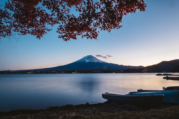 Photo une montagne avec un arbre au premier plan et un bateau sur le rivage.