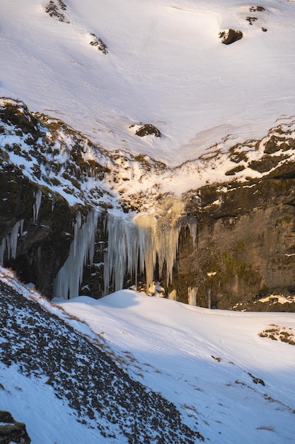 Montagne entièrement couverte de neige vers la cascade de Kvernufoss et une gorge avec des zones couvertes de neige