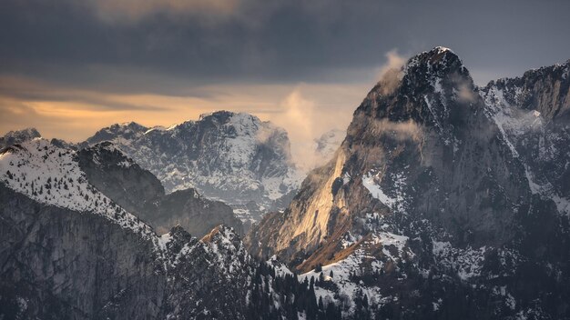 une montagne avec de la neige dessus et un ciel nuageux