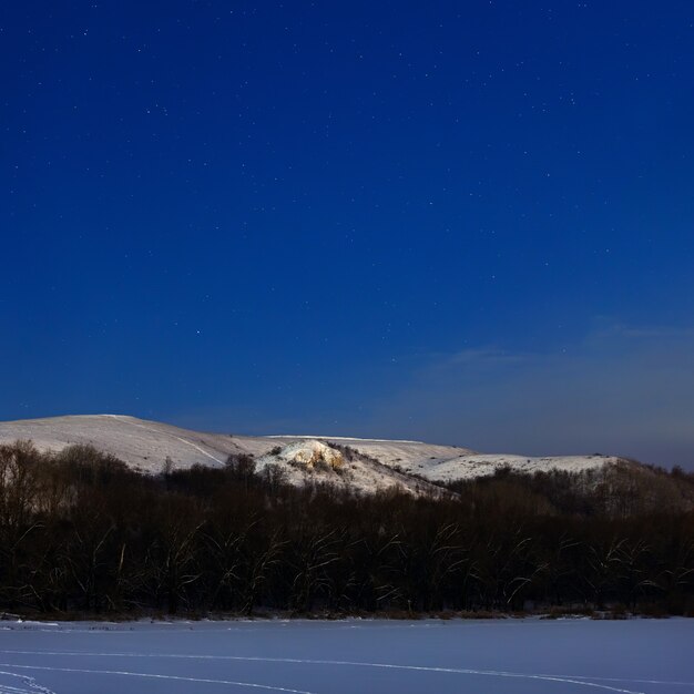 Montagne la nuit illuminée par la lumière de la pleine lune. Photo prise en hiver en Russie.