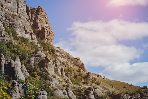 Montagne rocheuse avec des arbres contre le ciel avec des nuages colorés