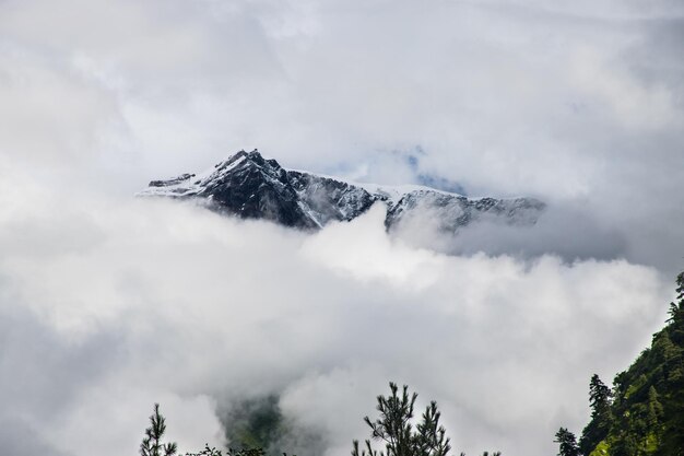 Photo montagne sombre et dramatique de l'himalaya dans les nuages cachés par le brouillard au népal