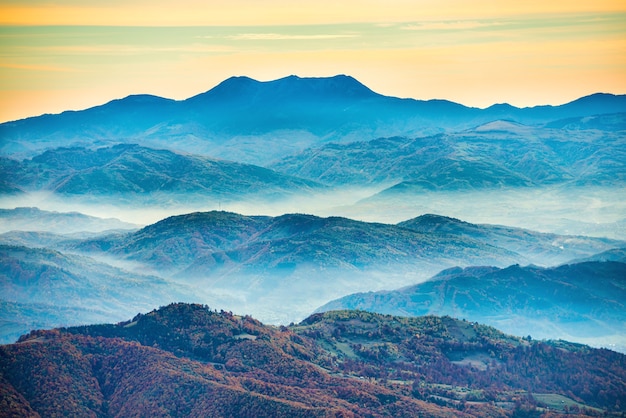 Montagnes bleues au coucher du soleil avec brume blanche sur les collines