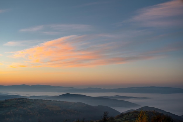 Des montagnes crème à l'aube dans le brouillard le ciel scintille de belles couleurs Le changement climatique de l'été à l'automne