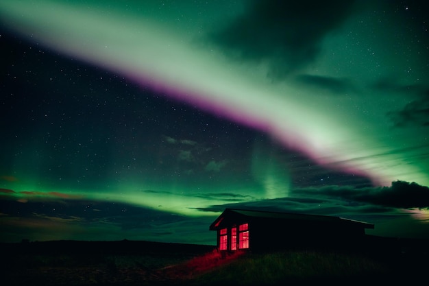 montagnes d'hiver la nuit petite maison sous le ciel rougeoyant avec des aurores boréales avec aurore