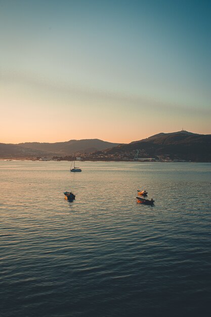 Les montagnes sur la mer et les bateaux pendant un coucher de soleil