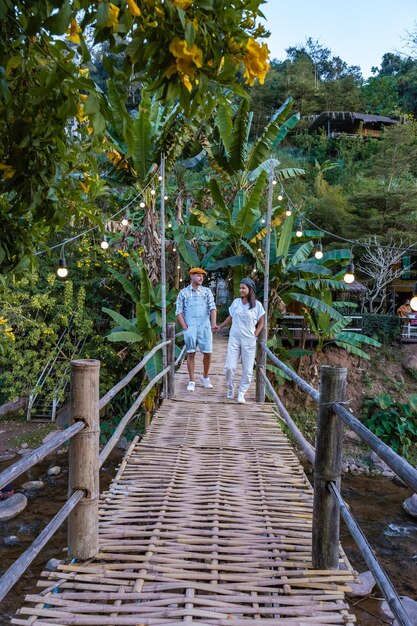 Les montagnes de Nan de la vallée de Sapan en Thaïlande avec des rizières et une forêt couple homme et femme marchant sur un pont en bambou en bois sur la rivière à Bo Klue