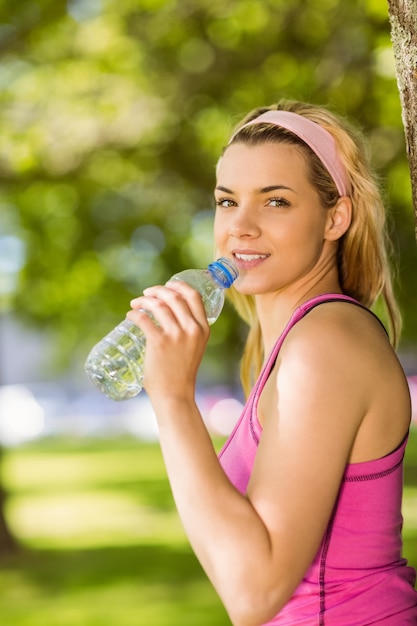 Monter la blonde appuyée contre l&#39;eau potable des arbres