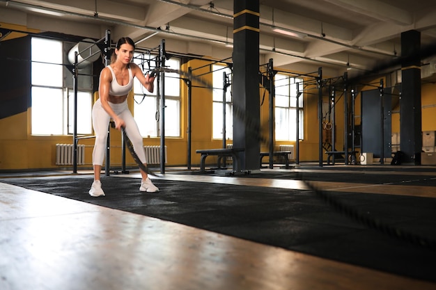 Monter la femme à l'aide de cordes de combat pendant l'entraînement en force au gymnase