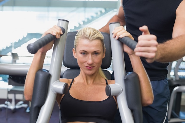 Monter la femme à l&#39;aide de la machine de fitness au gymnase