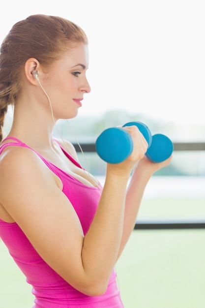 Monter la femme exerçant avec des haltères dans le studio de remise en forme