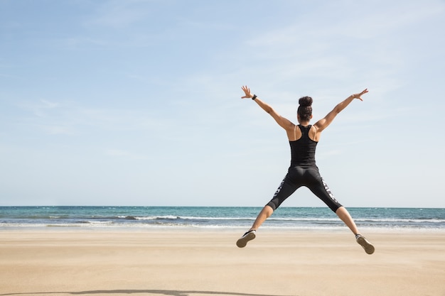 Monter la femme sautant sur le sable