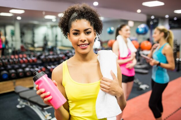 Monter la femme en souriant à la caméra dans la salle de musculation