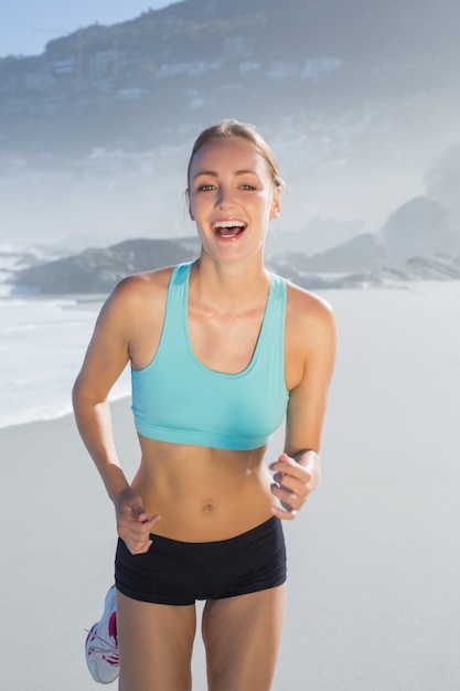 Monter la femme en souriant et faire du jogging sur la plage