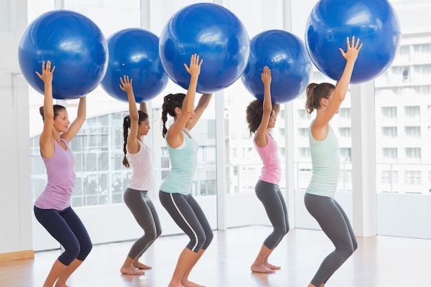 Photo monter les femmes tenant des ballons bleus de remise en forme dans la salle d'exercice