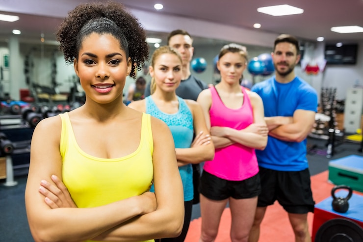 Photo monter les gens en souriant à la caméra dans la salle de musculation