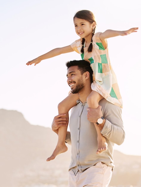 Monter haut sur les épaules de papa Photo recadrée d'un beau jeune homme portant sa fille sur ses épaules à la plage