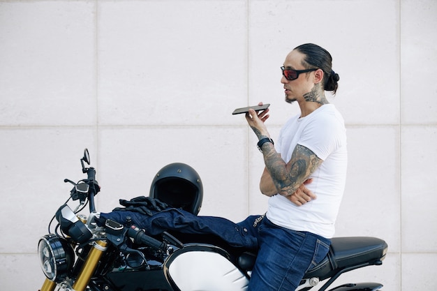 Monter un homme musclé dans des verres assis sur une moto et recoder un message vocal