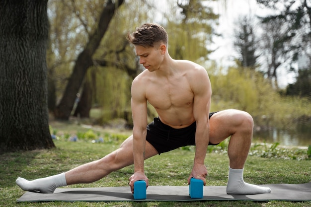 Photo monter l'homme qui s'étend avec des blocs de yoga plein coup