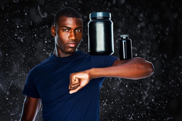 Photo monter l'homme tenant des bouteilles avec des suppléments sur ses biceps sur fond noir