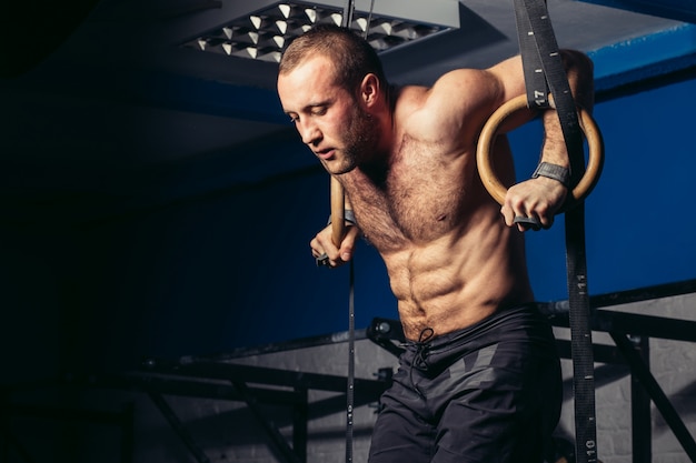 Monter l'homme tirant sur des anneaux de gymnastique.